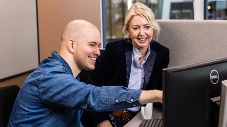 To personer som samarbeider foran en PC-skjerm
